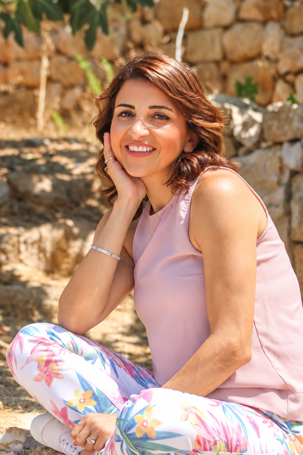 Dr. Jomana Elaridi seated outdoors against a stone wall